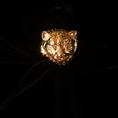 On a black background, sits a gold ring in the shape of a snow leopard.