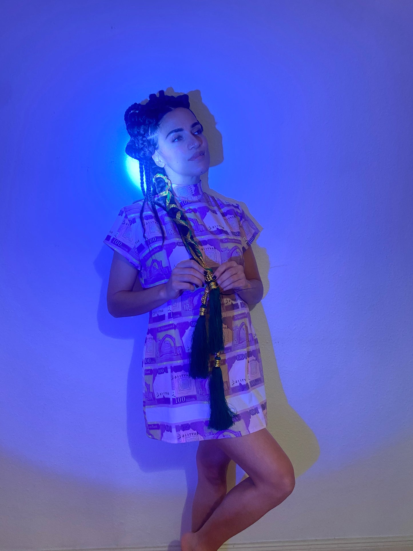 A blue light shines on a woman with a dress made of 100 Afghani mini dress.