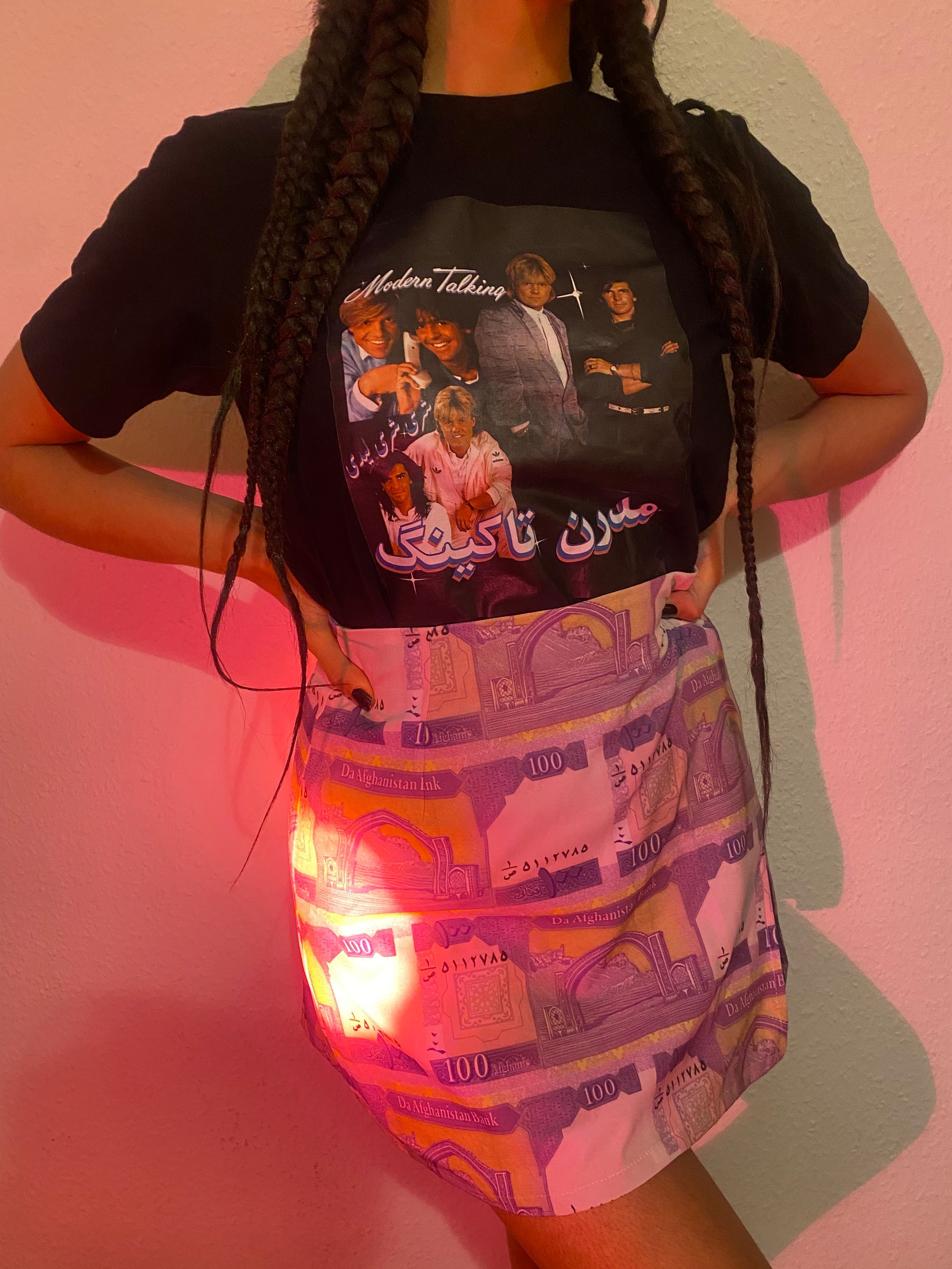 Torso and legs of a woman posing next to a wall with an ikat mini jupe and a graphic tee.