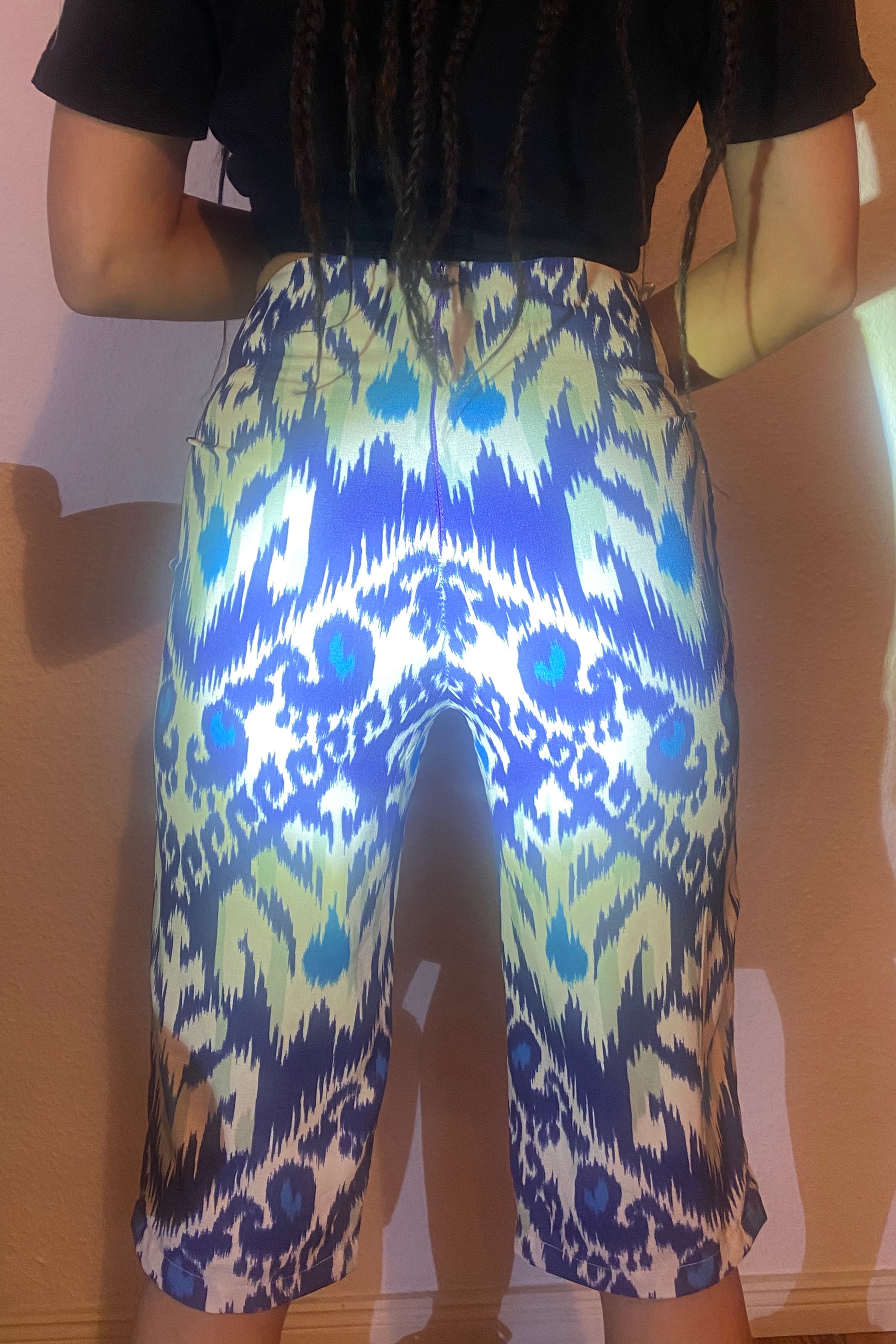 A light shines on the back of adras/ikat capri pants on a body, showing the details of the blues and white fabric.