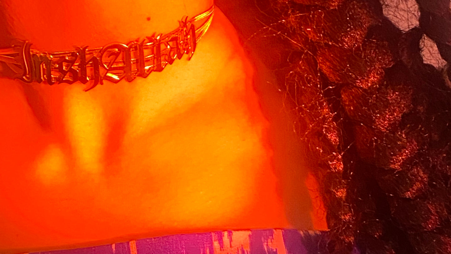 A close up of an InshAllah choker on the neck in gold with red lighting.