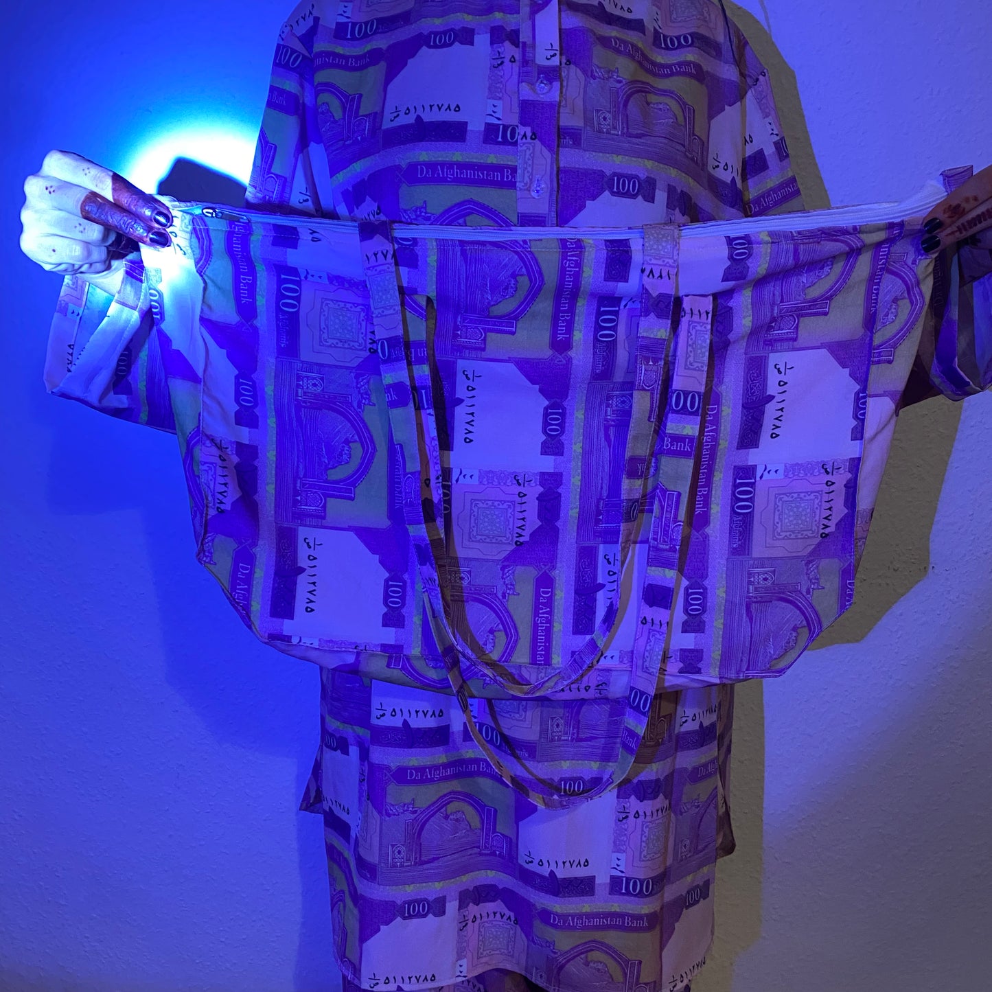 Moody blue lighting on a person holding up a tote bag.