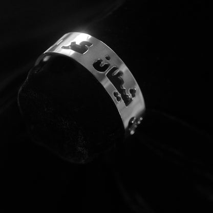 A silver bangle that says Gosh Shaitan Kaar in Dari against a black background.